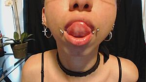 The young goth girl puts on nude lipstick and drools all over it, her tongue and saliva making a mess.