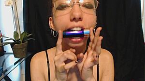 The young goth girl puts on nude lipstick and drools all over it, her tongue and saliva making a mess.