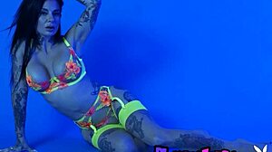 petite busty milf joanna angel undresses from her colorful neon lingerie, revealing big tits and naked body in a solo striptease